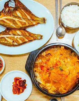 바삭하게 구운 가자미 한 마리와 김치를 넣어 빨갛게 끓인 곰치국, 흰쌀밥이 차려진 백반 한 상