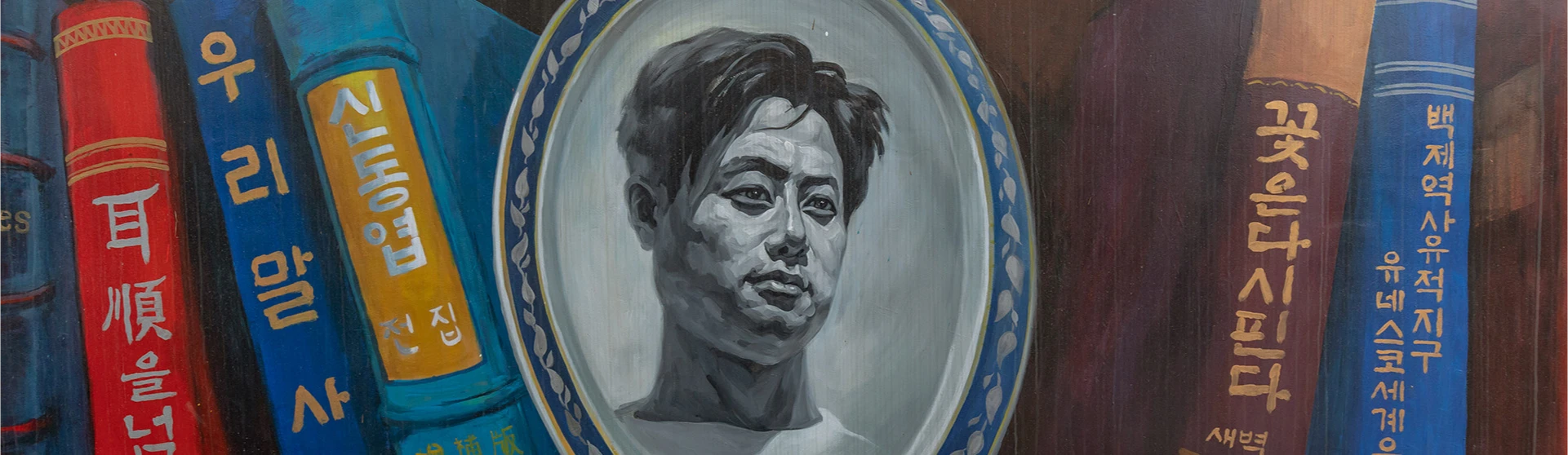 책등 모양 벽화 사이에 둥근 액자로 그려진 신동엽 시인의 초상이 자리한 꽃담길 벽화