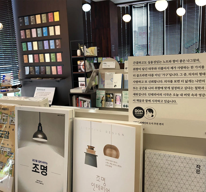 펜던트 조명 아래 색색의 색연필 견본과 큐레이션한 책들이 가지런히 진열된 서점 매대