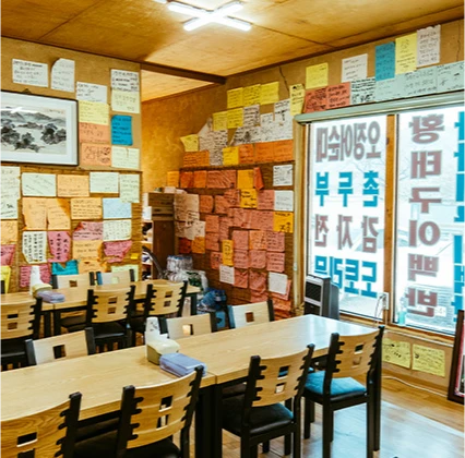 벽면 가득 손님들의 메모지가 붙어 있고 원목 테이블이 늘어선 순자집 곰치국 식당 내부
