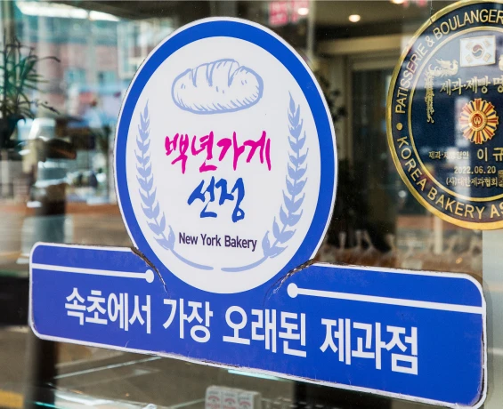 속초에서 가장 오래된 제과점임을 알리는 뉴욕제과의 백년가게 선정 스티커가 유리에 붙어 있다