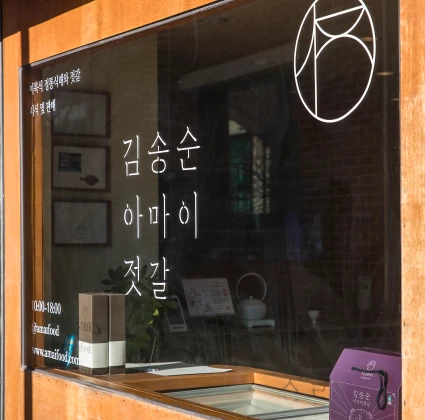김송순아마이젓갈 상호와 로고가 적힌 매장 유리창 너머로 정돈된 내부 공간이 비치는 모습