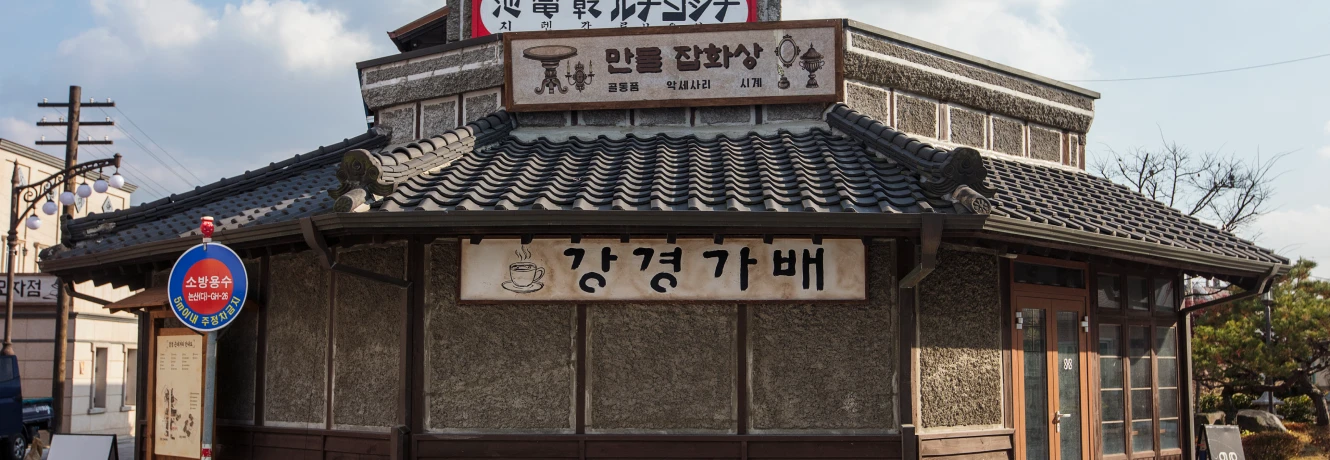 검은 기와와 목조 외벽에 강경가배라 적힌 간판을 단 옛 일본식 건물의 근대 카페 외관