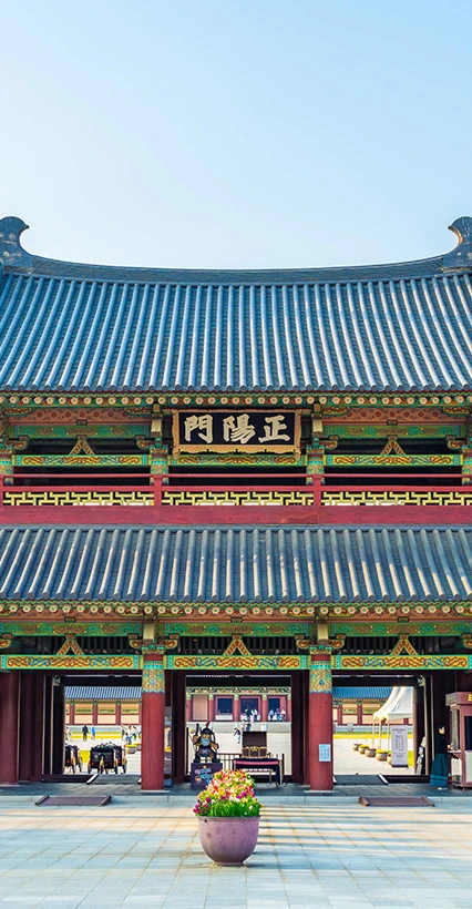 단청이 선명한 백제문화단지 정양문 문루를 정면에서 바라본 모습과 앞쪽 꽃 화분