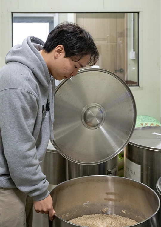 눈 덮인 바위 위에 놓인 떠먹는 제주 전통주 강술 유리병