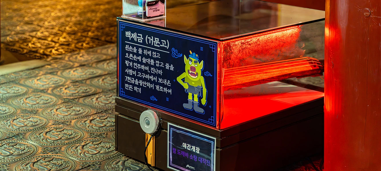 흰 분장에 검은 옷을 입은 귀신 분장 공연자가 어두운 야외에 서 있는 모습