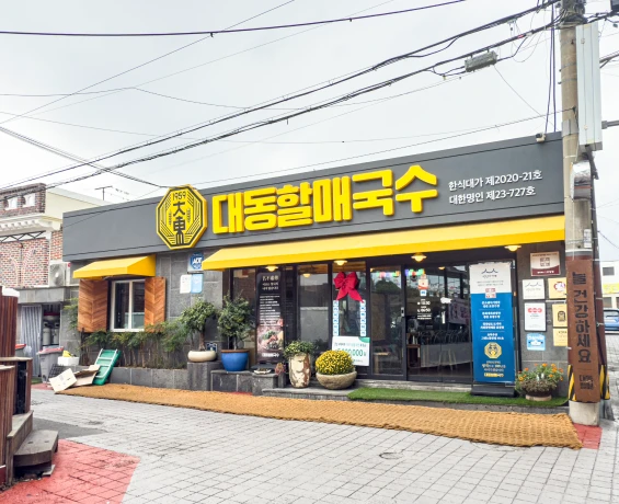 노란 간판에 대동할매국수 글자가 걸린 깔끔한 국수 전문점 외관과 황톳길 마당