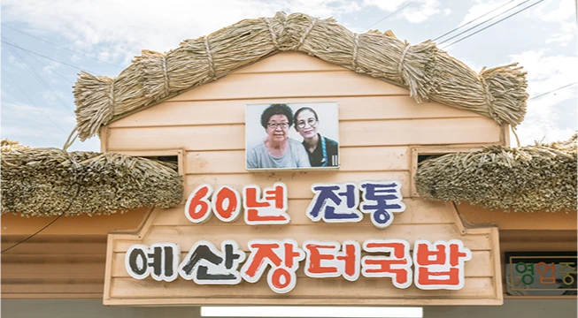 짚으로 엮은 처마 아래 60년 전통 예산장터국밥이라 적힌 간판