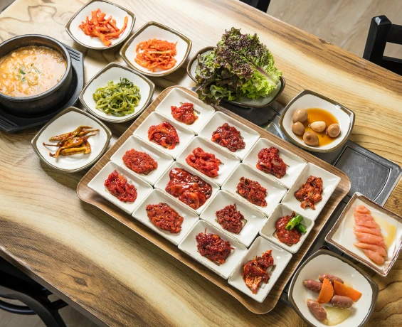 흰 접시에 가지런히 담긴 갖가지 붉은 젓갈과 청국장, 밑반찬, 쌈채소가 한상 가득 차려진 젓갈백반 상차림
