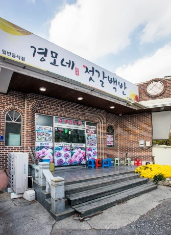 붉은 벽돌 건물에 경모네 젓갈백반 간판을 내건 강경의 젓갈백반 식당 외관과 계단 앞 화분들