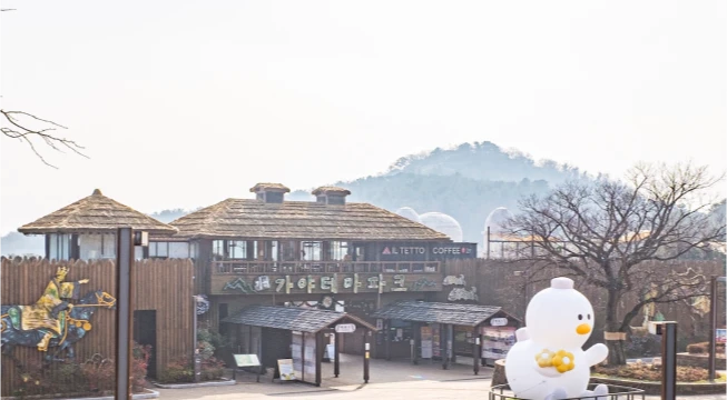 가야테마파크 입구의 한옥형 건물과 캐릭터 조형물, 멀리 보이는 산