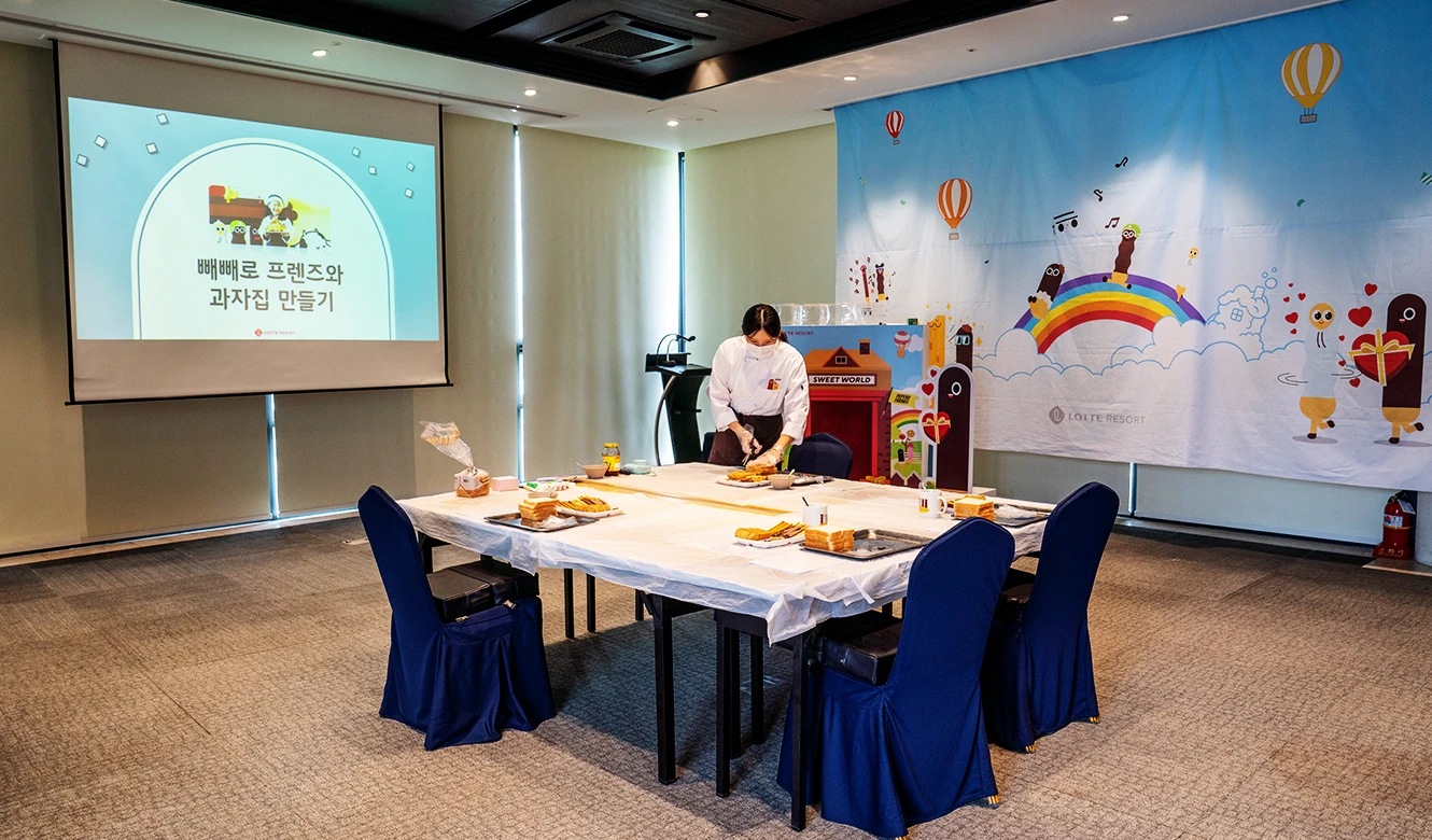 쿠킹 클래스 시작 전 재료가 차려진 테이블과 안내 화면이 켜진 백상룸 강의실 전경