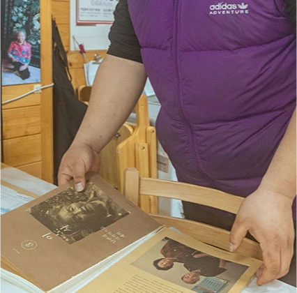 보라색 조끼를 입은 사장이 1대 창업주 이야기가 실린 자료를 펼쳐 보이는 모습