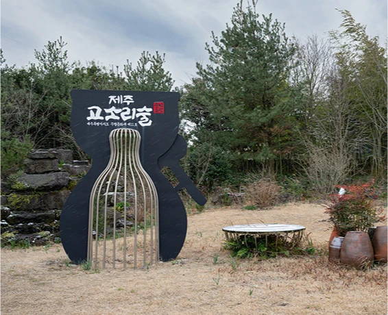 병 모양으로 만든 제주 고소리술 조형물이 세워진 잔디 마당과 솔숲