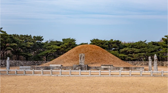 잔디밭 위로 둥글게 솟은 수로왕릉의 원형 봉토무덤과 둘레의 석물, 난간