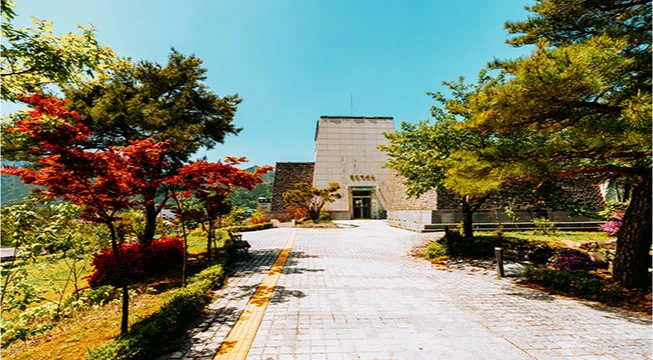 붉은 단풍나무와 소나무가 늘어선 돌길 끝에 자리한 발해 역사관 석조 건물
