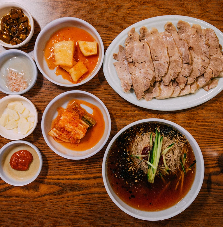 편육과 막국수, 충청도식 김치와 밑반찬이 함께 차려진 막국수집 한 상을 위에서 본 모습