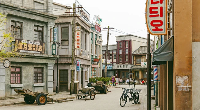 한글과 한자 간판이 큼지막하게 걸린 건물과 자전거가 늘어선 1950년대 거리 세트