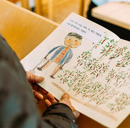 할아버지와 감나무가 그려진 손그림 그림책을 펼쳐 든 모습, 서툰 그림과 손글씨가 정겨운 동화책