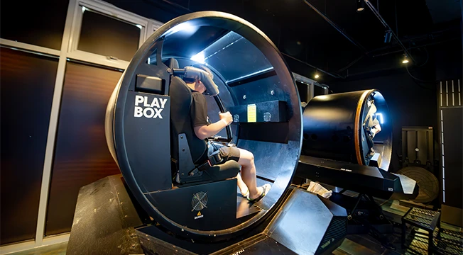 원형 캡슐 안에 앉아 VR 기기를 쓰고 체험에 몰입한 플레이박스 이용객