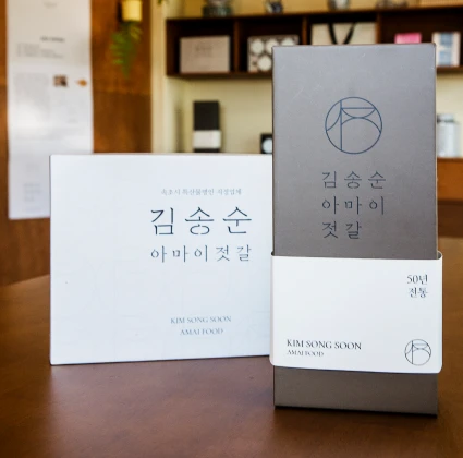 매장 테이블에 나란히 진열된 김송순아마이젓갈의 흰색과 회색 선물 포장 상자
