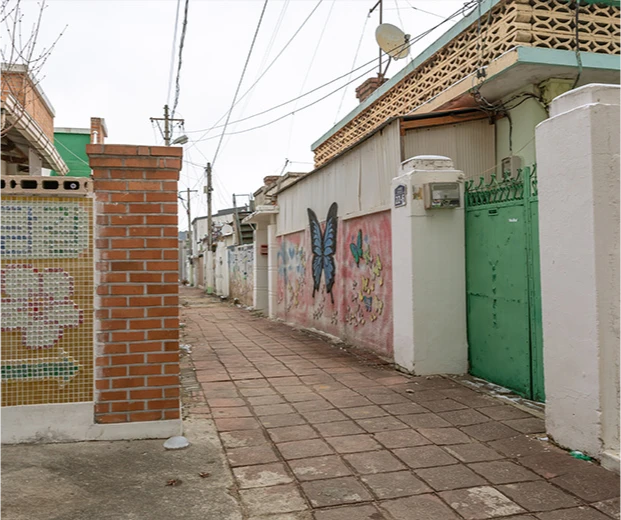 벽돌 기둥과 나비, 꽃 벽화로 꾸며진 담장이 늘어선 부여 꽃담길의 정겨운 골목