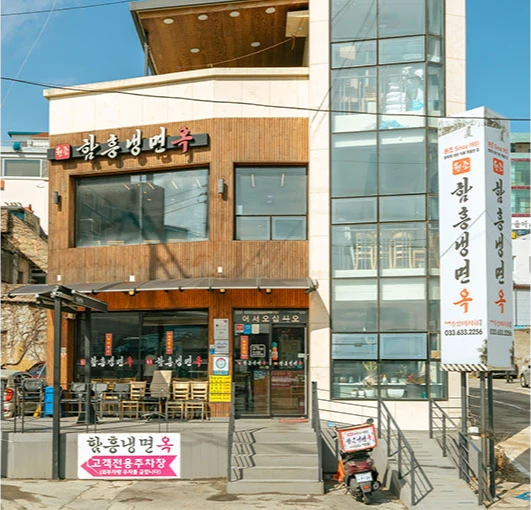 함흥냉면옥 간판이 붙은 이층 건물 외관, 맑은 하늘 아래 거리에 선 노포 전경
