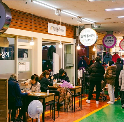 감자옹심이 간판이 걸린 실내 식당가에서 손님들이 테이블에 둘러앉아 식사하는 모습