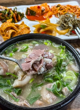 고기와 밥을 한 술 떠올린 고기국밥과 정갈하게 곁들인 밑반찬 상차림