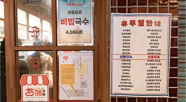 비빔국수 포스터와 점포별 휴무일 안내문이 붙은 가게 창가
