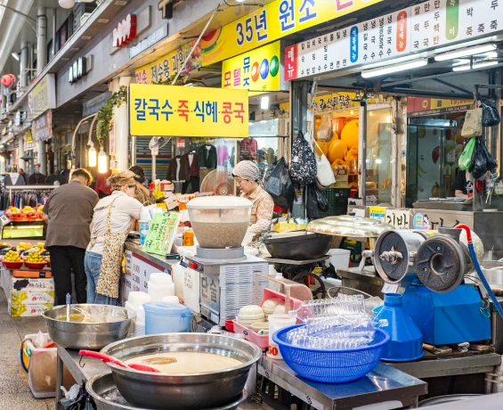 칼국수 죽 식혜를 파는 노란 간판 아래 손님과 상인이 분주한 시장 분식 점포 풍경