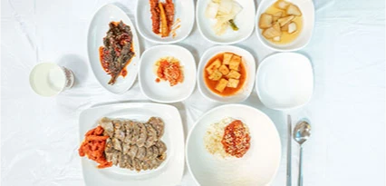 흰 접시에 가지런히 담긴 아바이순대와 밥, 생선구이, 여러 밑반찬이 차려진 한상차림