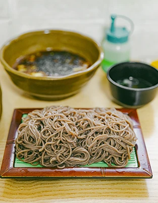 대나무 발에 담긴 메밀소바와 간장 육수 그릇이 놓인 반월소바의 메밀소바