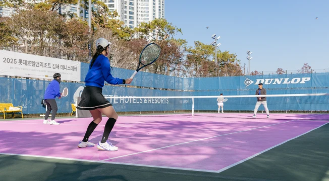 파란 상의의 여성 선수가 리턴을 준비하며 라켓을 겨눈 복식 경기 장면