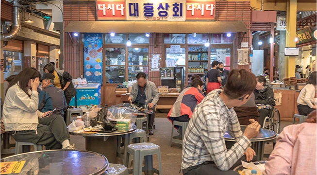 대흥상회 간판 아래 둥근 테이블마다 손님들이 둘러앉아 식사하는 예산시장 내부 풍경