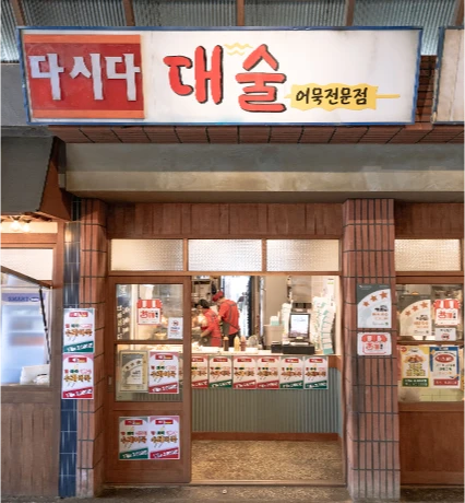 다시다 로고와 함께 걸린 대술어묵 간판과 손님이 주문하는 가게 입구
