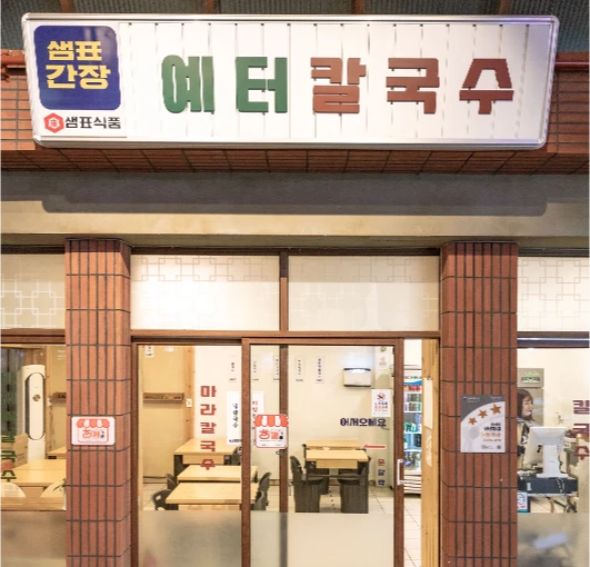 샘표간장 광고가 함께 걸린 예터칼국수 간판과 가게 외관