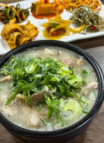 쪽파를 듬뿍 올린 뽀얀 고기국밥과 여러 가지 밑반찬이 차려진 풍년식당 한 상