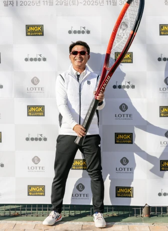 대회 포토월 앞에서 라켓을 어깨에 걸친 채 환하게 웃는 남성 참가자