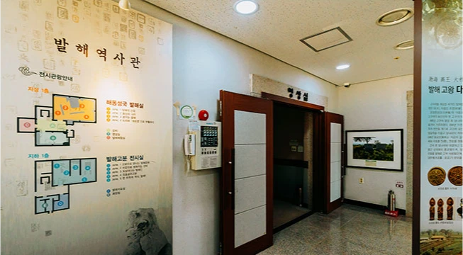 발해 역사관 입구의 전시실 안내도와 출입문, 한쪽에 유물 사진이 걸린 내부 모습