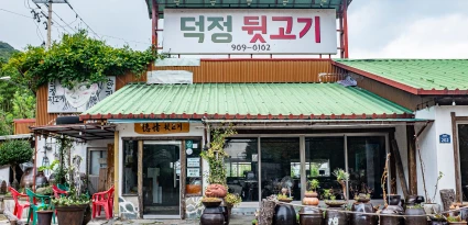 초록 지붕과 덕정 뒷고기 간판이 걸린 시골 정취가 묻어나는 뒷고기 전문점 외관
