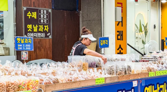 옛날과자와 부각을 비닐봉지에 담아 진열한 시장 가게에서 상인이 물건을 정리하는 모습