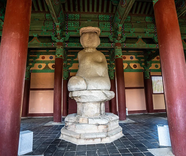 화려한 단청 누각 안에 모셔진 둥근 보개를 쓴 정림사지 석불좌상의 정면 모습