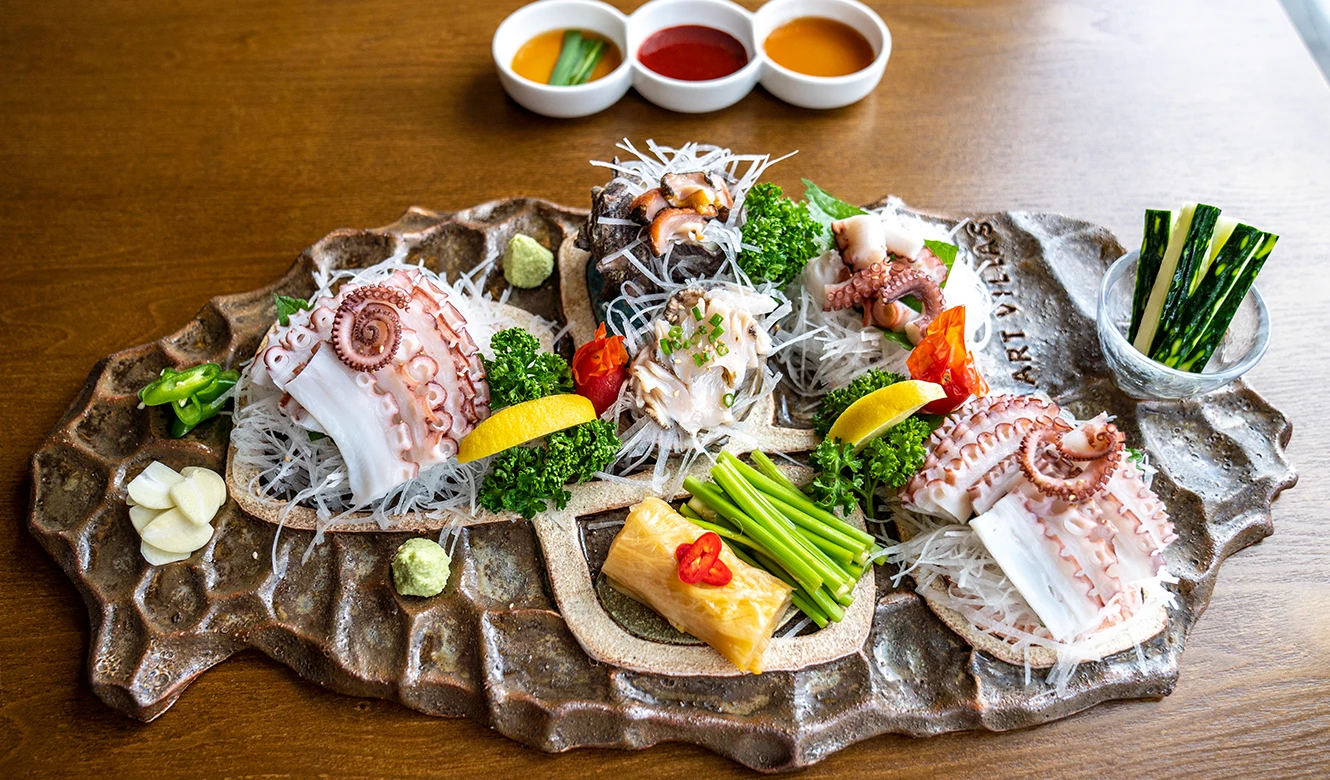 제주 모양 돌 접시에 돌문어 숙회와 전복, 뿔소라회, 채소를 가지런히 차려 위에서 담은 모습