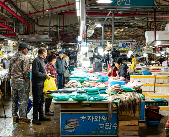 갓 손질한 생선을 얼음 위에 펼친 어물전 앞에서 흥정을 나누는 손님과 상인들
