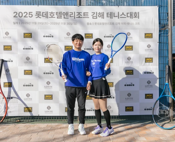 파란 단체복을 입은 남녀 참가자가 라켓을 들고 대회 포토월 앞에서 나란히 선 모습