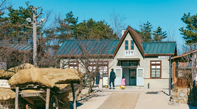 옛 속초역을 재현한 박공지붕 건물과 앞쪽에 놓인 초가 수레가 보이는 전시