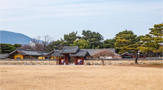 돌담과 솟을삼문 너머로 소나무가 늘어선 수로왕릉의 너른 전경