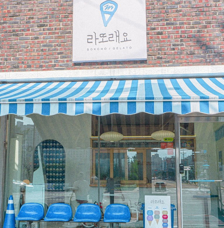 파란 줄무늬 차양과 파란 의자가 놓인 젤라토 가게 라또래요의 외관