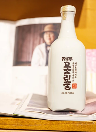 대표 사진이 실린 지면 위에 세워진 백자 병 모양의 제주 고소리술